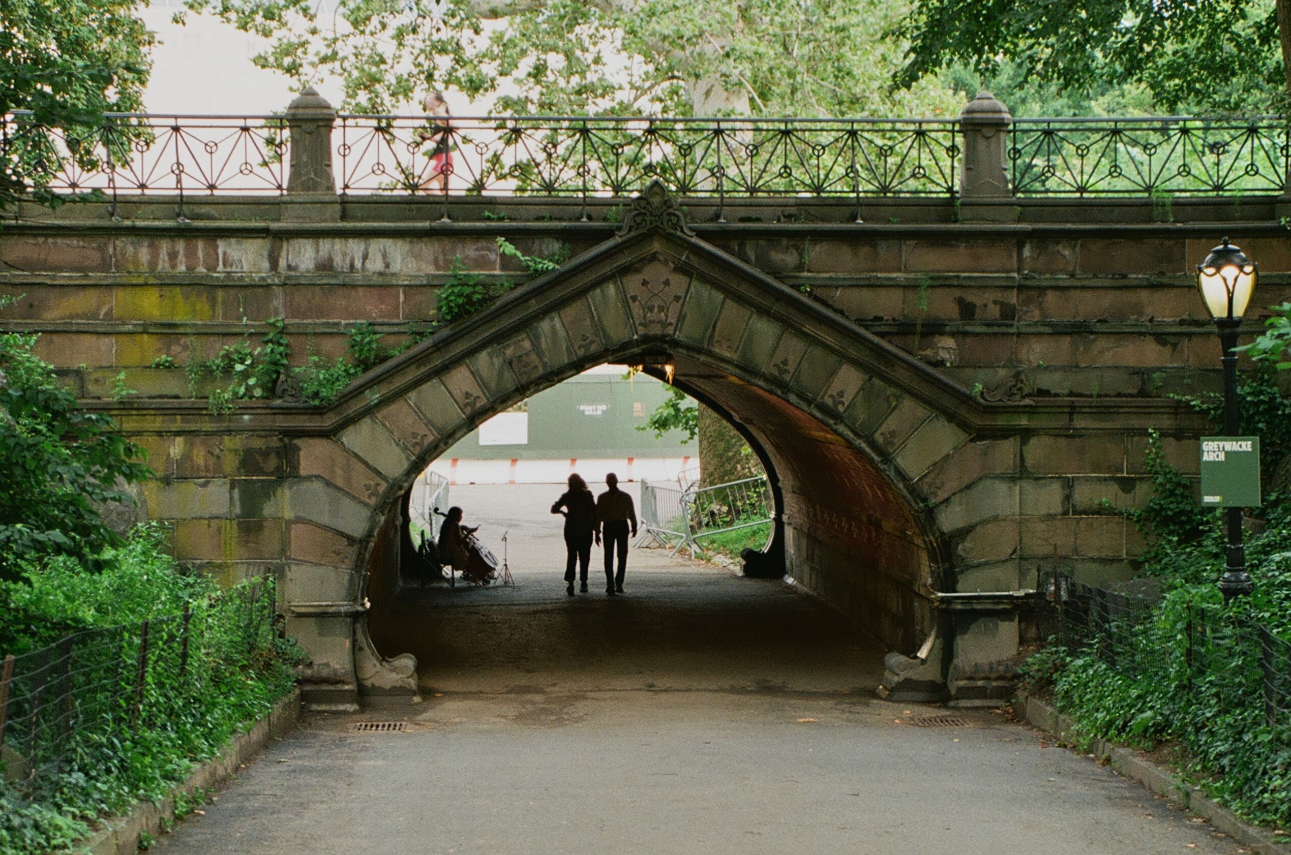 Figures silhouetted beneath a stone park arch