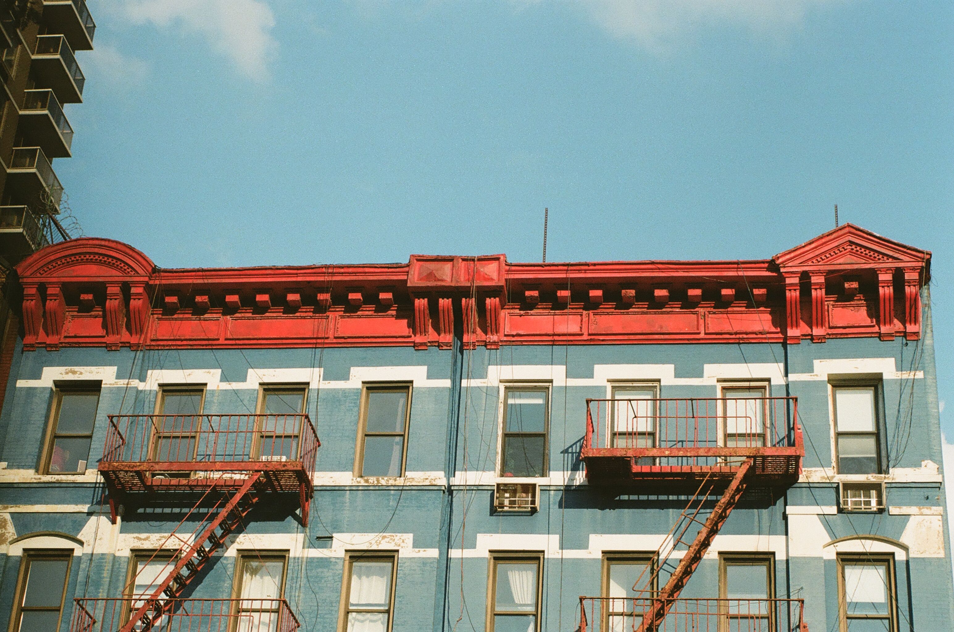 Blue building facade with a bright red cornice