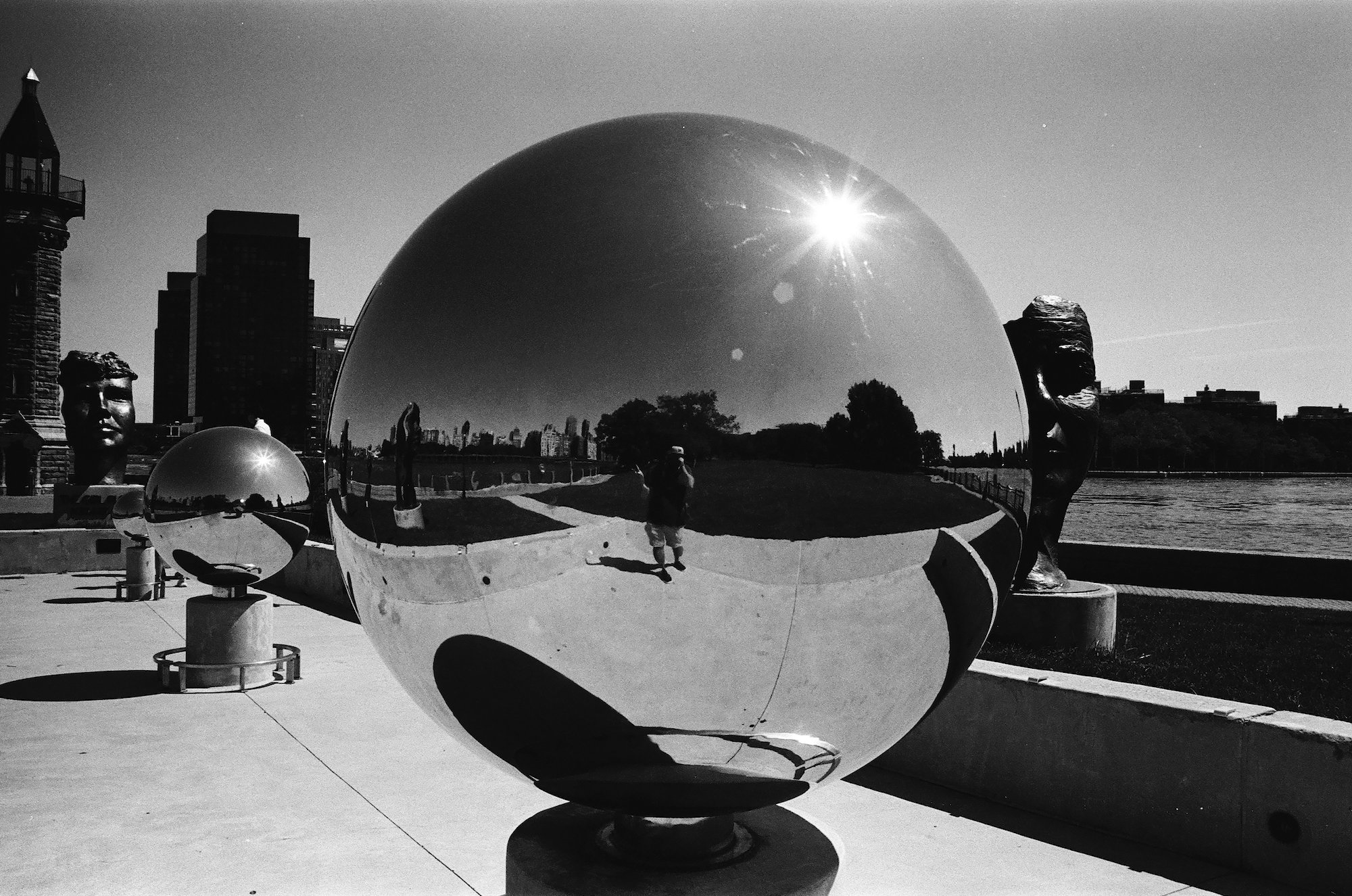Reflective spheres, lighthouse, and a visitor in bright sunlight