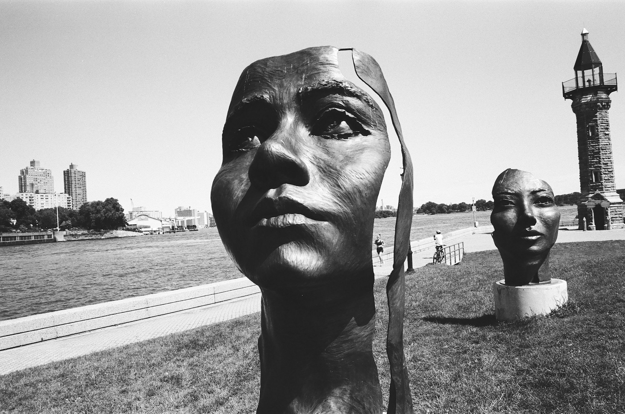 Large bronze face sculptures beside the Roosevelt Island lighthouse